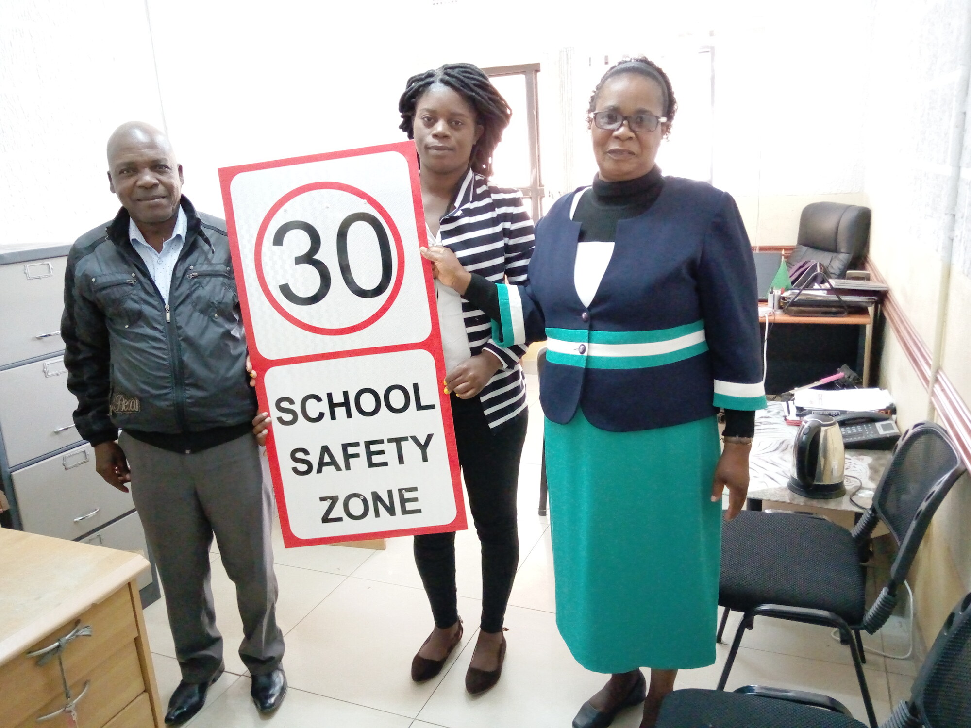 ZRST representatives presenting a 30 kilometre per hour school safety zone sign