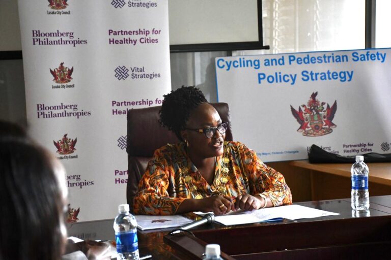 Lusaka Mayor holding a pen over a policy document at the signing table.